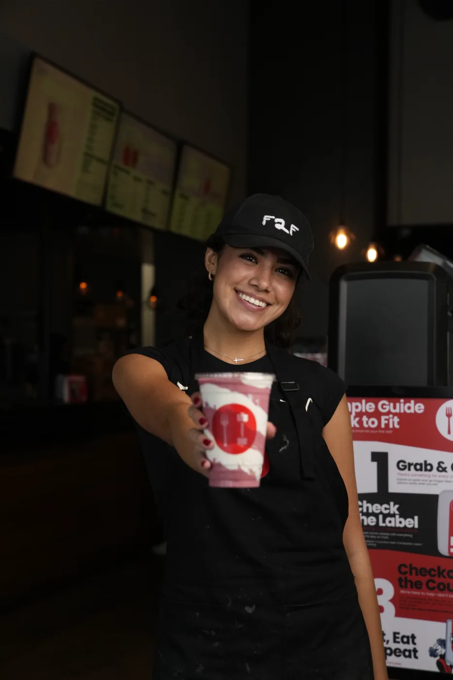 A smiling Fork to Fit team member offering a drink in a branded cup