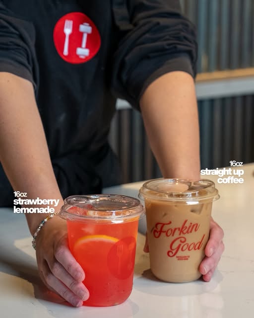 A person wearing the Fork to Fit logo presents strawberry lemonade and iced coffee in branded cups.